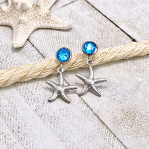 Crystal Stud Starfish Earrings are placed on a thick rope on a white wooden surface.