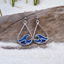 Load image into Gallery viewer, Curling Wave Earrings are displayed by being placed on top of a driftwood on the sand.