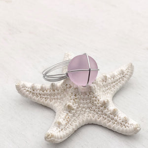 Hand-Wired Pink Sea Glass Ring is placed on top of a white dried artificial starfish.