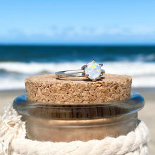 Load image into Gallery viewer, Minimalist Opal Ring displayed by being placed on top of a cork with a blurred beach background.