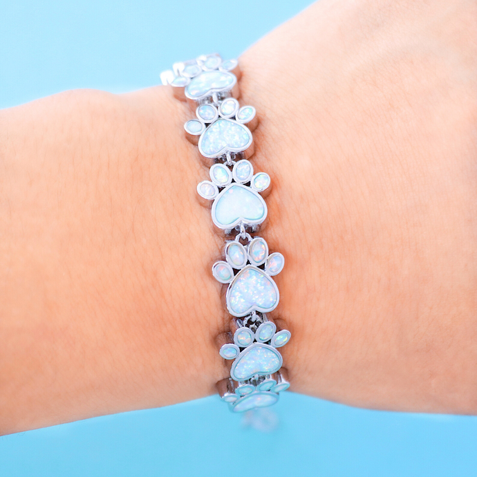 Opal Love Paw Bracelet in White is displayed by being worn around a woman's wrist