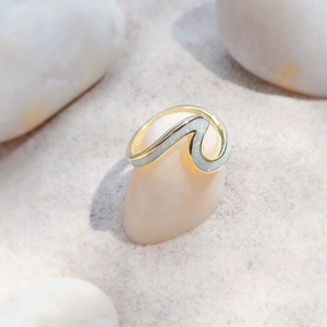 Opal Wave Ring is displayed by being placed on top of a smooth white rock.