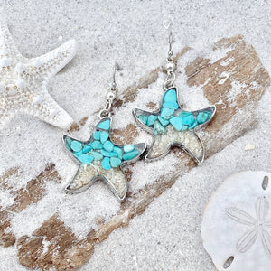 Sand Starfish Earrings in Teal Turquoise are displayed by being placed on top of a sand covered driftwood.