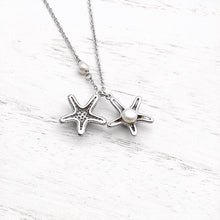 Load image into Gallery viewer, Starfish Hidden Pearl Necklace displayed on a white wooden surface.