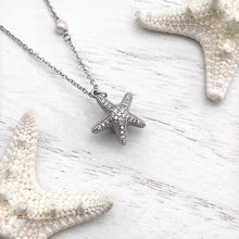 Load image into Gallery viewer, Starfish Hidden Pearl Necklace displayed on a white wooden surface.