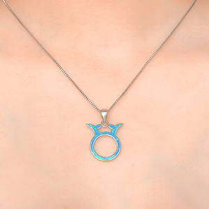 Opal Taurus Necklace displayed closely by being worn around a woman's neck.