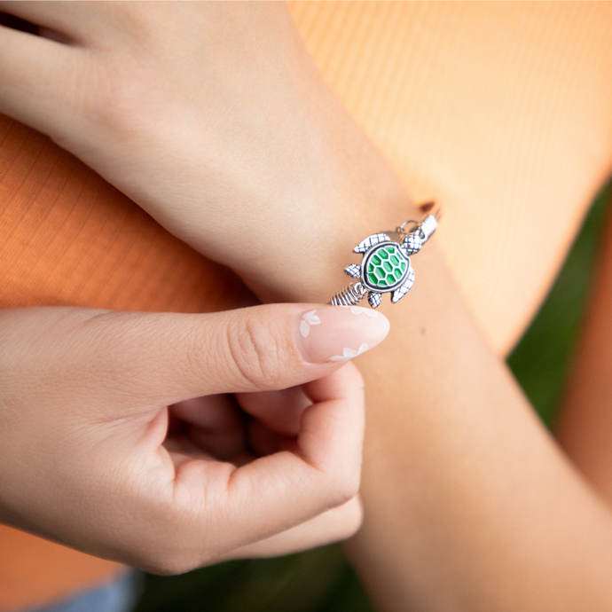 Charming Sea Turtle Bracelet worn on a woman's wrist and held by the other hand.