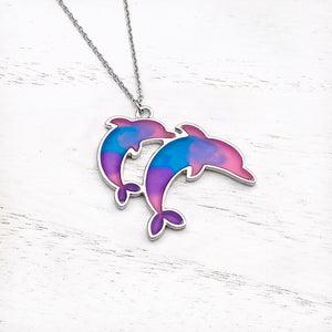 Colorful Enamel Dolphin Necklace displayed on a white wooden surface.