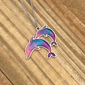 Colorful Enamel Dolphin Necklace displayed on a wooden surface.