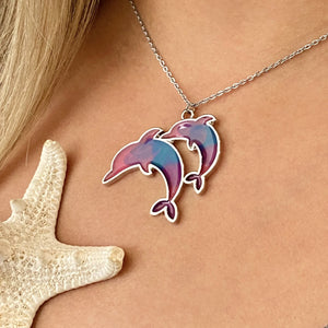 Colorful Enamel Dolphin Necklace displayed by being worn around a woman's neck.
