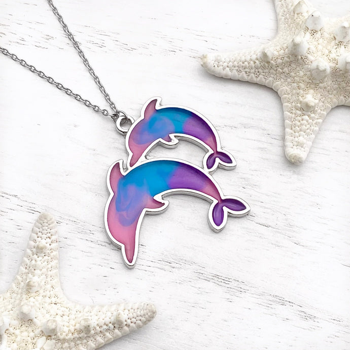Colorful Enamel Dolphin Necklace displayed on a white wooden surface.
