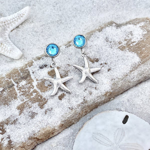 Crystal Stud Starfish Earrings are displayed by being placed on top of a sand covered driftwood.