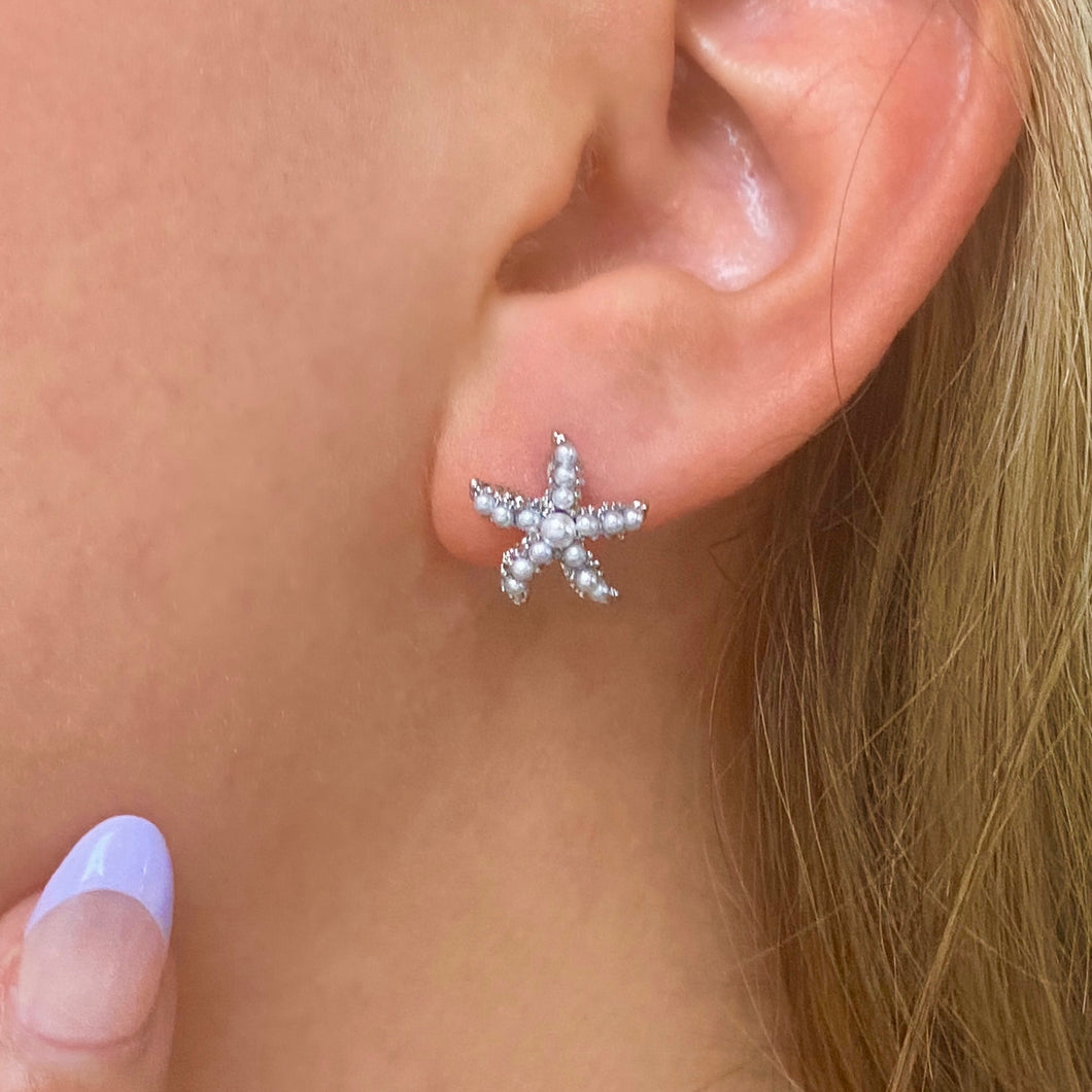 Dainty Pearl Starfish Stud Earring displayed closely by being worn on a woman's ear.