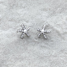 Load image into Gallery viewer, Dainty Pearl Starfish Stud Earrings are displayed on a sandy surfcae.