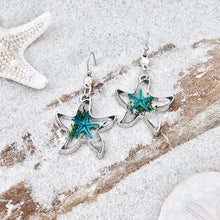 Load image into Gallery viewer, Deep In The Ocean Starfish Earrings are displayed by being placed on top of a sand covered driftwood.