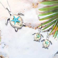 Load image into Gallery viewer, Deep in the Ocean Sea Turtle earrings and necklace showcased on a sandy surface with a palm leaf accent.