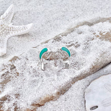 Load image into Gallery viewer, Dolphin Stud Earrings are displayed by being placed on top of a sand covered driftwood.