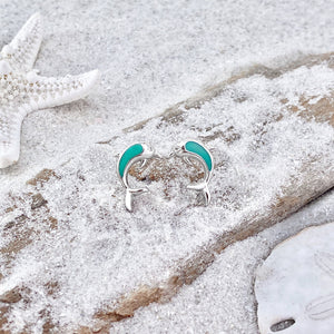 Dolphin Stud Earrings are displayed by being placed on top of a sand covered driftwood.
