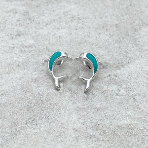 Dolphin Stud Earrings displayed on a white beach sand.