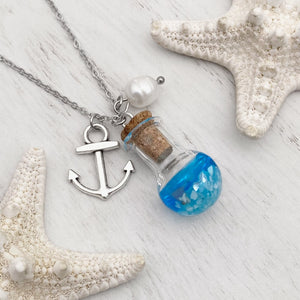 Drift Bottle Anchor Necklace displayed on a white wooden surface.