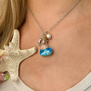 Drift Bottle Mermaid Necklace displayed by being worn around a woman's neck.