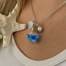 Load image into Gallery viewer, Drift Bottle Sand Dollar Necklace displayed by being worn around a woman&#39;s neck.