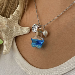 Drift Bottle Sand Dollar Necklace displayed by being worn around a woman's neck.