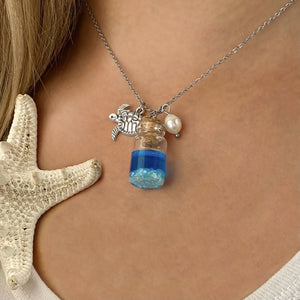 Drift Bottle Sea Turtle Necklace displayed by being worn around a woman's neck.