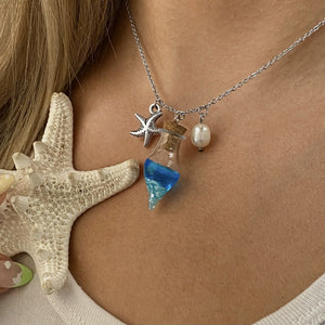 Drift Bottle Starfish Necklace displayed by being worn around a woman's neck.