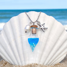 Load image into Gallery viewer, Drift Bottle Starfish Necklace is hung on a big white oyster shell on the beach.
