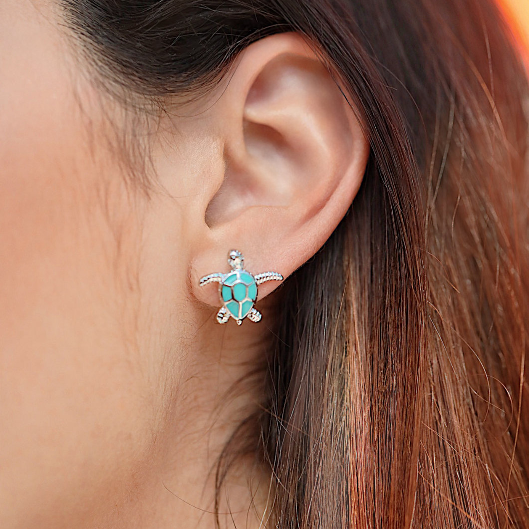 Enamel Sea Turtle Studs is displayed up close by being worn on a woman's ear.