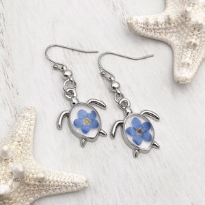 Forget Me Not Sea Turtle Earrings displayed on a white wooden surface, ideal spring jewelry.