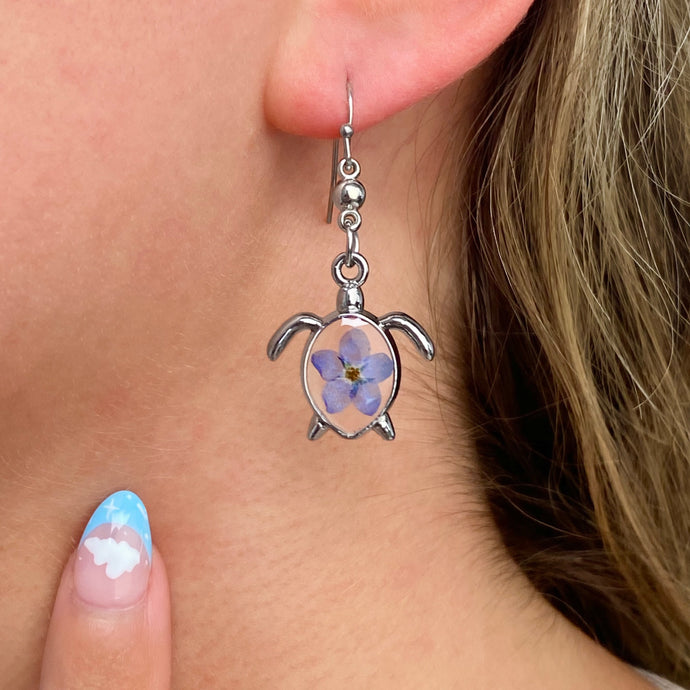Forget Me Not Sea Turtle Earrings worn on a woman's ear, ideal for ocean-inspired jewelry.