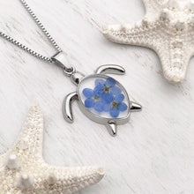 Load image into Gallery viewer, Forget Me Not Sea Turtle Necklace displayed on a white wooden surface, ideal spring jewelry.