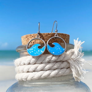 Glittering Wave Earrings placed on a cork that is covering a glass bottle.