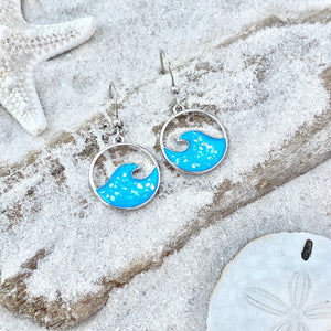 Glittering Wave Earrings are displayed by being placed on top of a sand covered driftwood.
