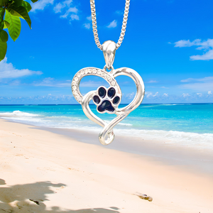 Heart Paw Necklace hanging close for a shot with a beach background.