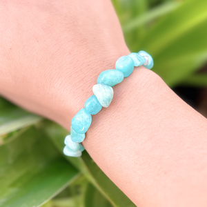 Larimar Bracelet displayed by being worn around a woman's wrist with a blurred leafy background.