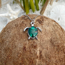 Load image into Gallery viewer, Malachite Sea Turtle Necklace is displayed on top of a dried coconut.
