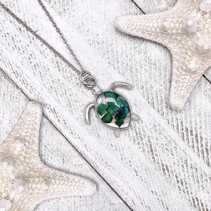 Malachite Sea Turtle Necklace displayed on a white wooden surface.