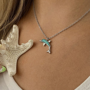 Ocean Treasure Sand Dolphin Necklace displayed by being worn around a woman's neck