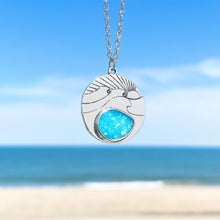 Load image into Gallery viewer, The Ocean Treasure Sand Wave Necklace is hanging up close with a blurry beach background.