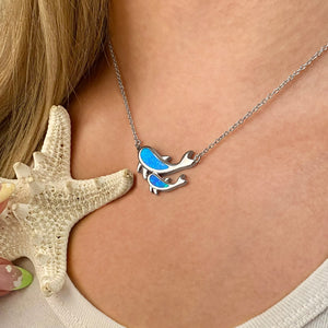Opal Dolphin Duo Necklace is displayed up close by being worn around a woman's neck.