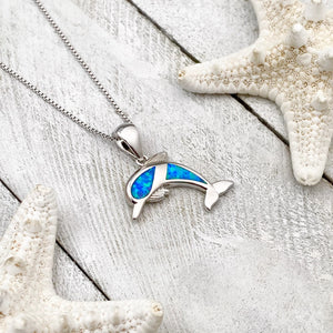 Opal Dolphin Necklace displayed on a white wooden surface.