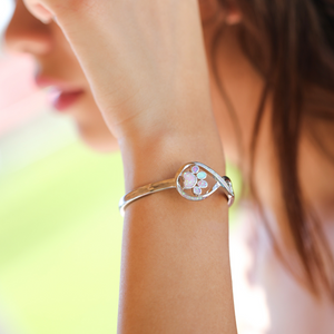 Opal Infinity Love Paw Cuff Bracelet in Pink being worn on a woman's arm.