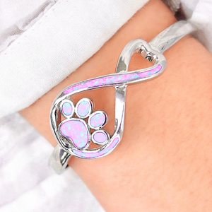 Opal Infinity Love Paw Cuff Bracelet in Pink, worn on a woman's arm, captured in a close-up shot.