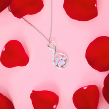 Load image into Gallery viewer, Opal Infinity Love Paw Necklace in Pink displayed on top of a pink surface with rose petals around it.