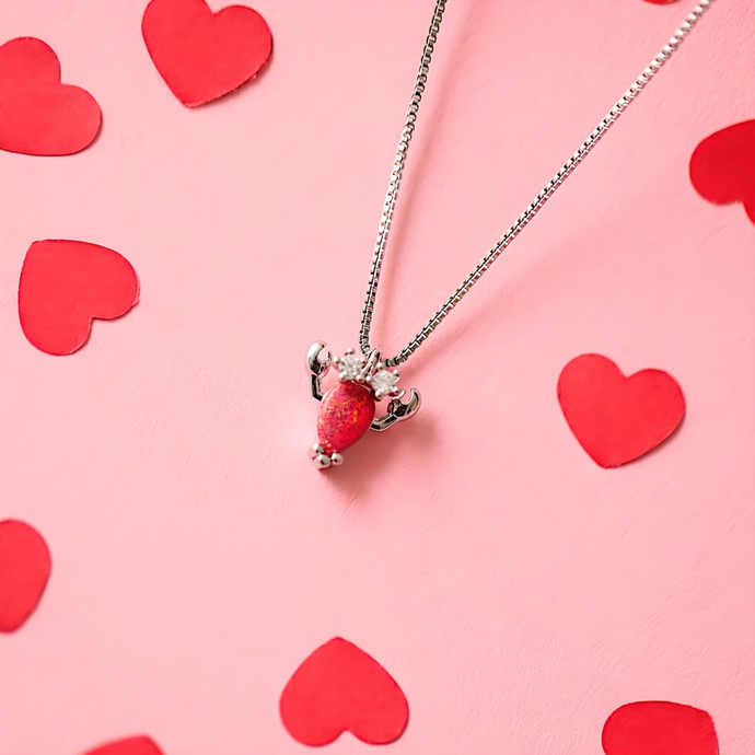 Opal Lobster Necklace elegantly showcased on a pink surface adorned with heart motifs.