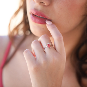 A hand positioned near a woman's lips is displaying the Opal Lobster Ring.