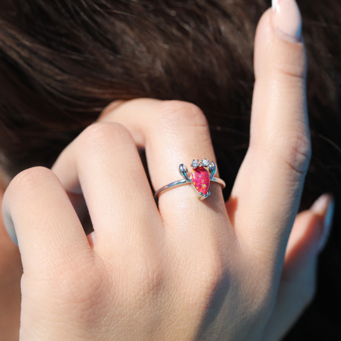 A woman's hand fixing her hair is displaying the Opal Lobster Ring.
